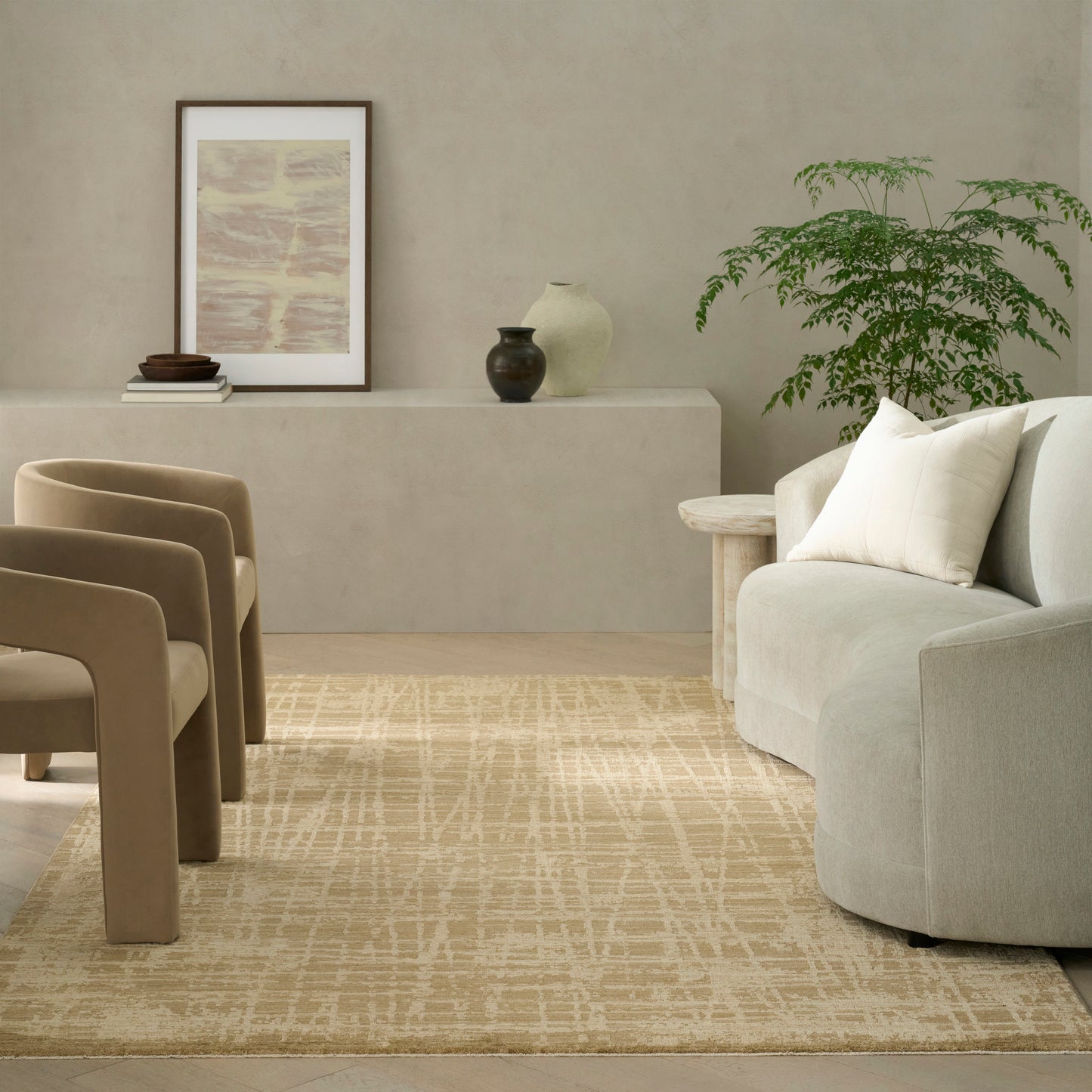 Neutral living room with beige armless chairs, light gray sofa, cream geometric rug, potted plant & framed abstract art.