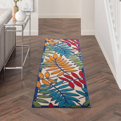 Rectangular tropical leaf runner rug with multicolor leaves on white background and a deep blue border in a modern hallway.