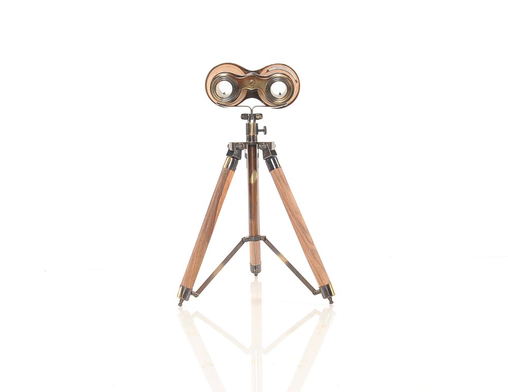 Vintage brass binoculars on a wooden tripod stand, antique-style desk display.