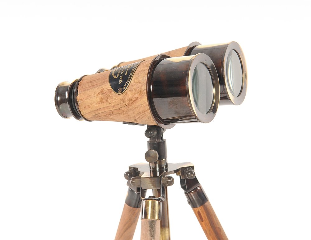 Antique wooden telescope with brass fittings mounted on a wooden tripod, nautical spyglass style.