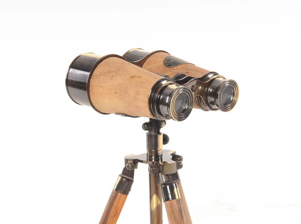 Vintage wooden binoculars with brass fittings mounted on a wooden tripod.