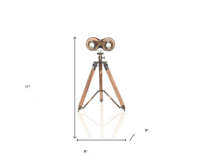 Vintage brass binoculars on a wooden tripod with copper accents; retro nautical display decor.