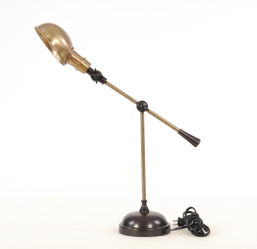 Brass desk lamp with bowl-shaped shade, adjustable arm and joints, on a round dark base, corded.