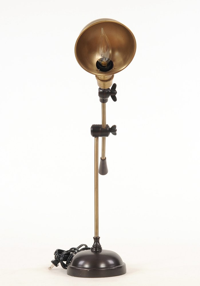 Vintage brass floor lamp with copper-toned shade, adjustable joints, black hardware, and a grey pull chain; industrial style.