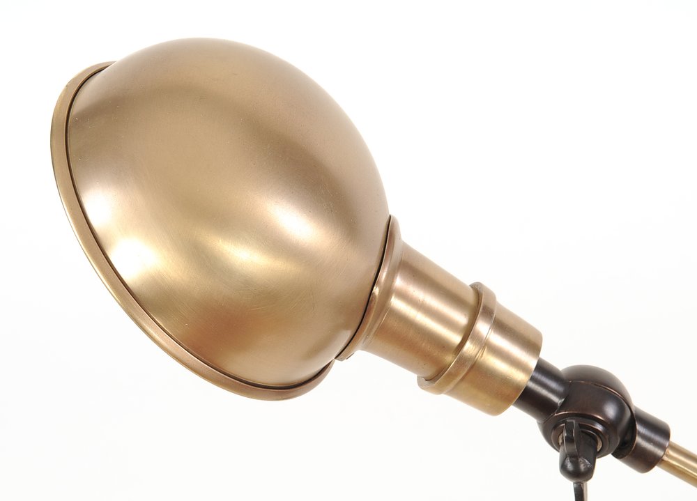 Gold brass microphone head with a spherical dome on a black adjustable gooseneck stand.