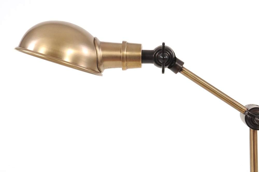 Brass adjustable desk lamp with dome shade and articulated arm in vintage industrial style.