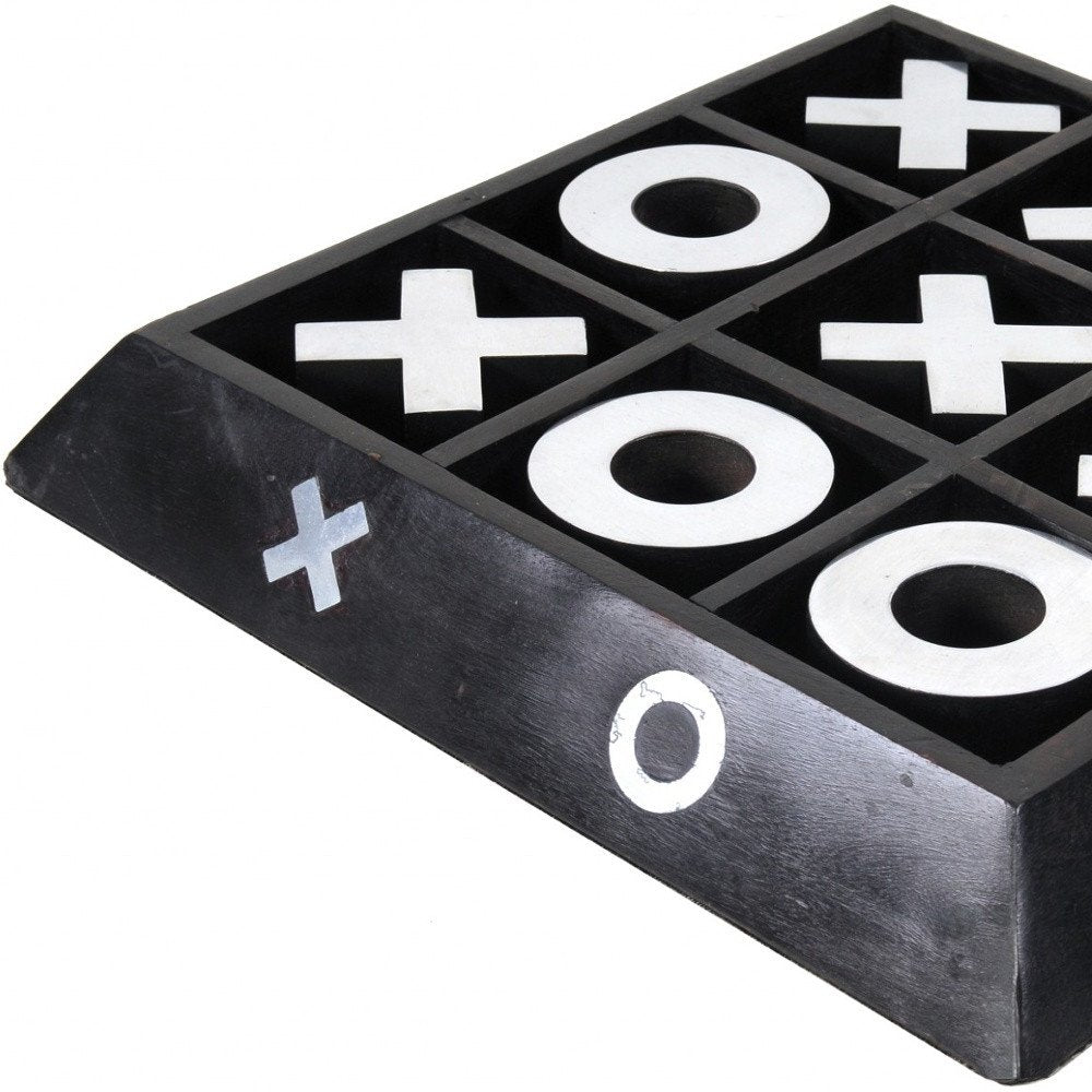 Black wooden tic-tac-toe board with white X and O symbols in a 3x3 grid, angled corner view.