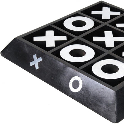 Black wooden tic-tac-toe board with white X and O symbols in a 3x3 grid, angled corner view.