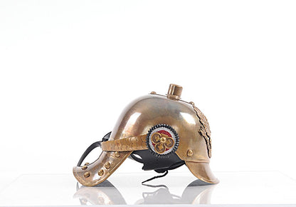 Brass steampunk helmet with riveted shell, leather chin strap, cog emblem, and ornate rear crest.