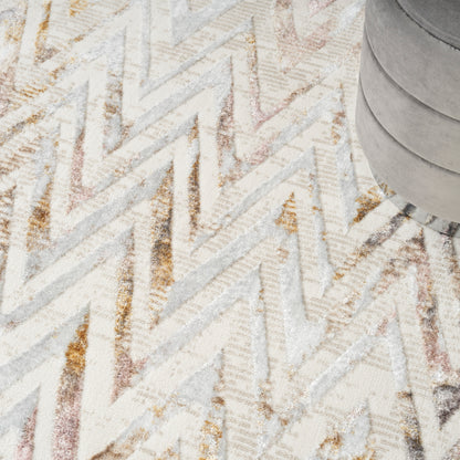 Neutral chevron rug in cream, beige, gray with gold accents; gray round ottoman on top-right.