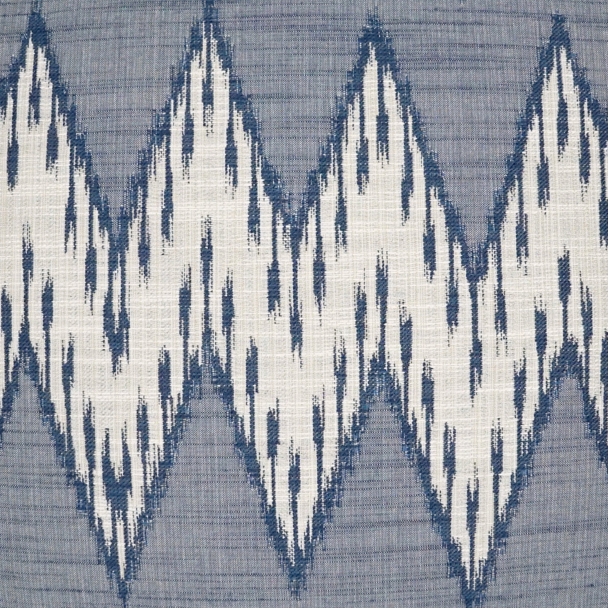 Blue-gray fabric with bold white zigzag ikat diamond pattern.
