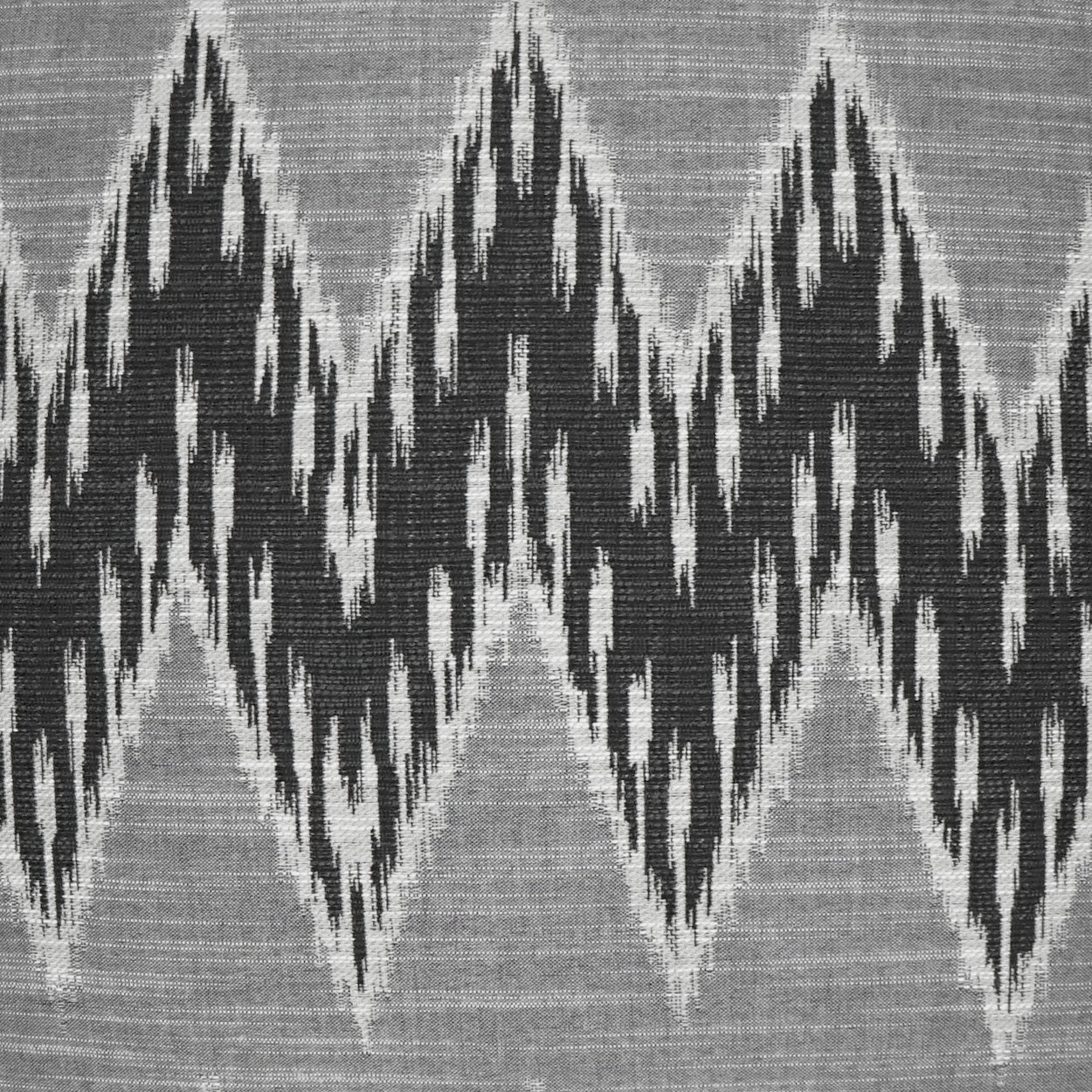 Grey fabric pillow with bold black chevron pattern; geometric weave, ideal for decor accents.