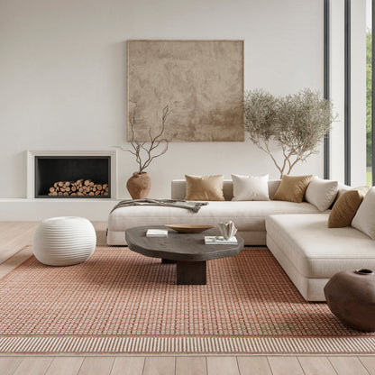 Neutral living room with beige sectional, dark round coffee table, orange rug, white pouf, pottery vases, olive trees, art.