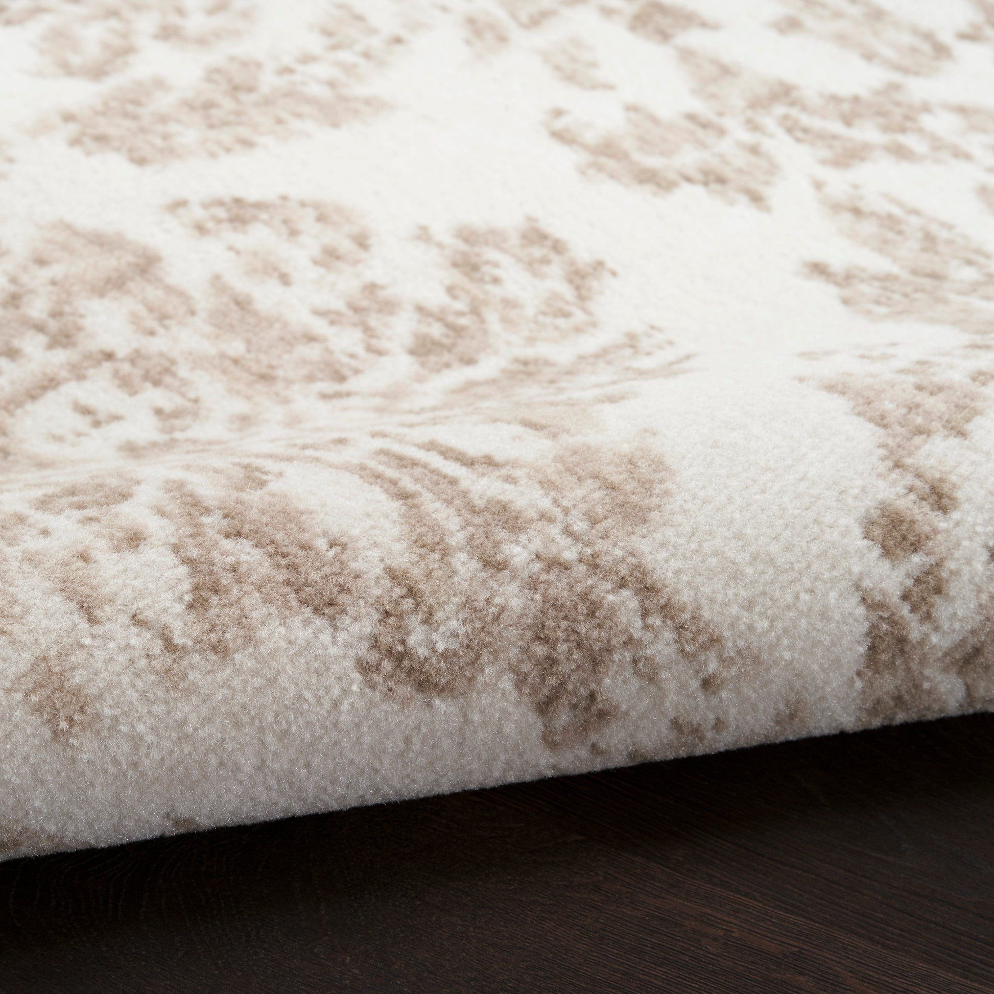 Cream & beige damask-patterned plush rug, round 5' diameter, on dark wood floor.