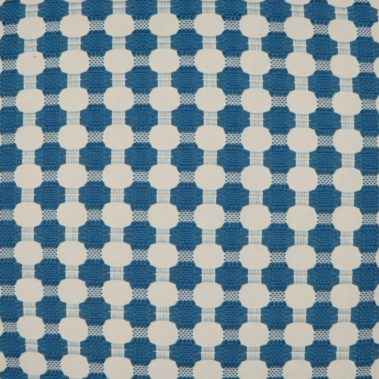 Blue fabric with a repeating grid of white circular motifs forming a dotted lattice pattern.