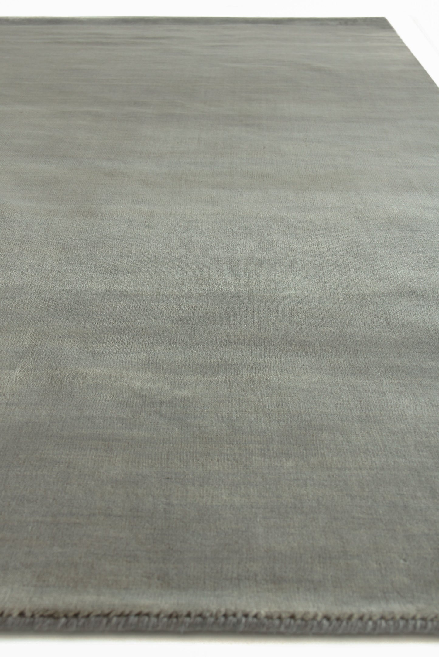 Rectangular wool dove indoor hand-loomed rug with subtle tonal texture and fringe along one edge.