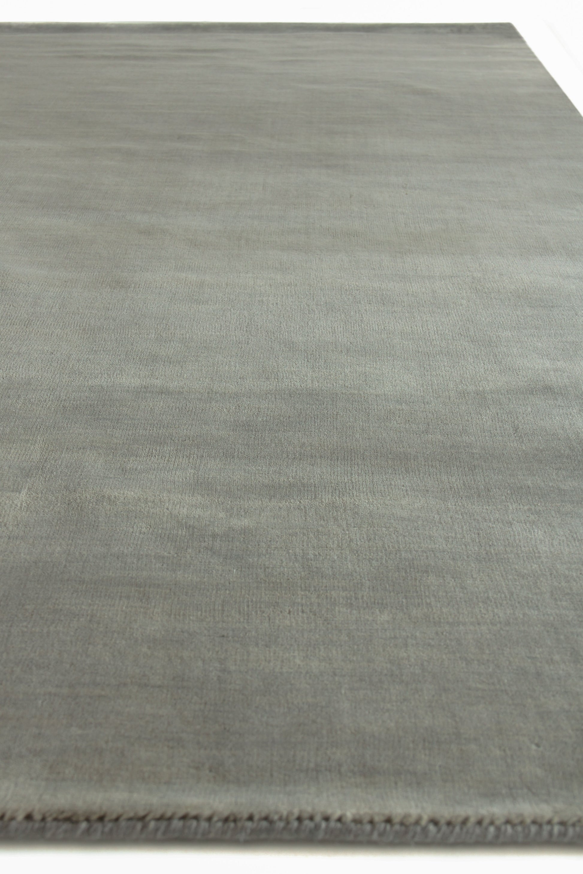 Rectangular wool dove indoor hand-loomed rug with subtle tonal texture and fringe along one edge.