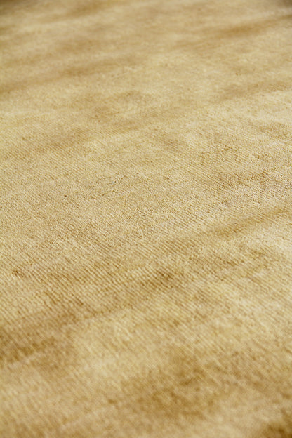 Beige wool rug close-up showing a soft nap and warm golden-brown tones; hand-loomed weave.
