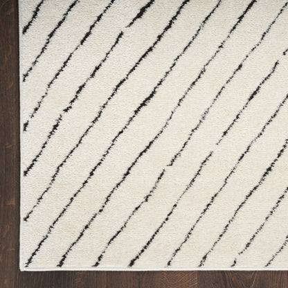 Cream plush rug with bold black diagonal stripes; modern geometric design on dark wood floor.