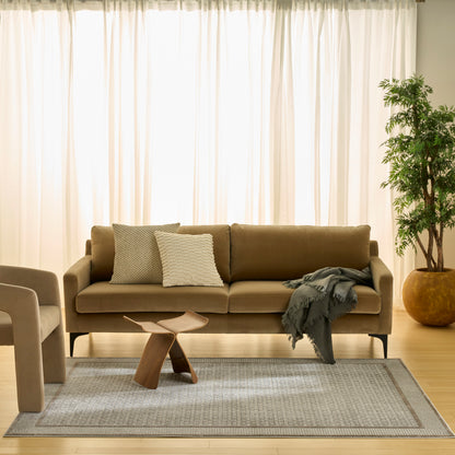 Beige fabric sofa with two textured cushions, gray throw, sculptural wood coffee table, light gray rug and potted plant.