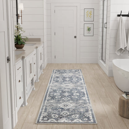 Blue-gray patterned runner rug on light wood floor in a white-paneled bathroom with a freestanding tub and vanity.