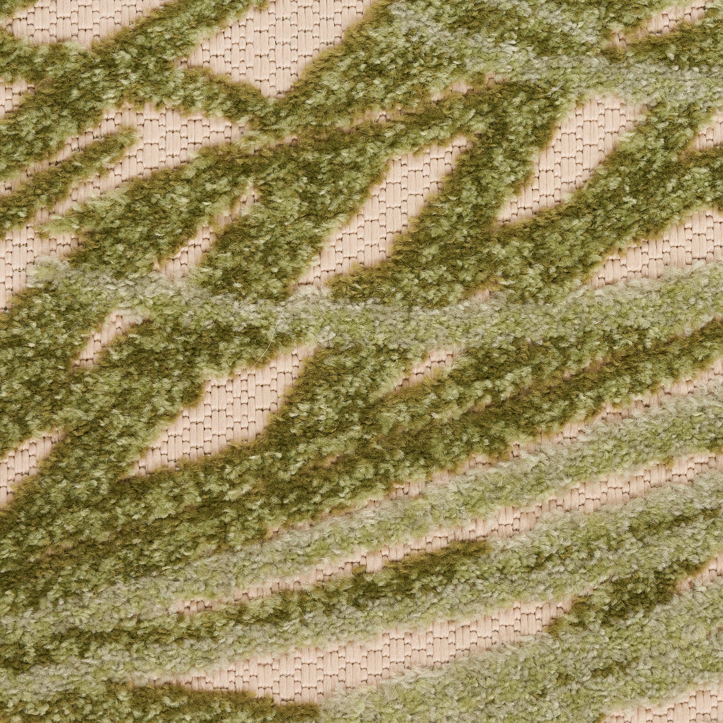 Close-up of an olive-green shaggy stripe rug on a beige woven base; textured, wavy diagonal chevron pattern.
