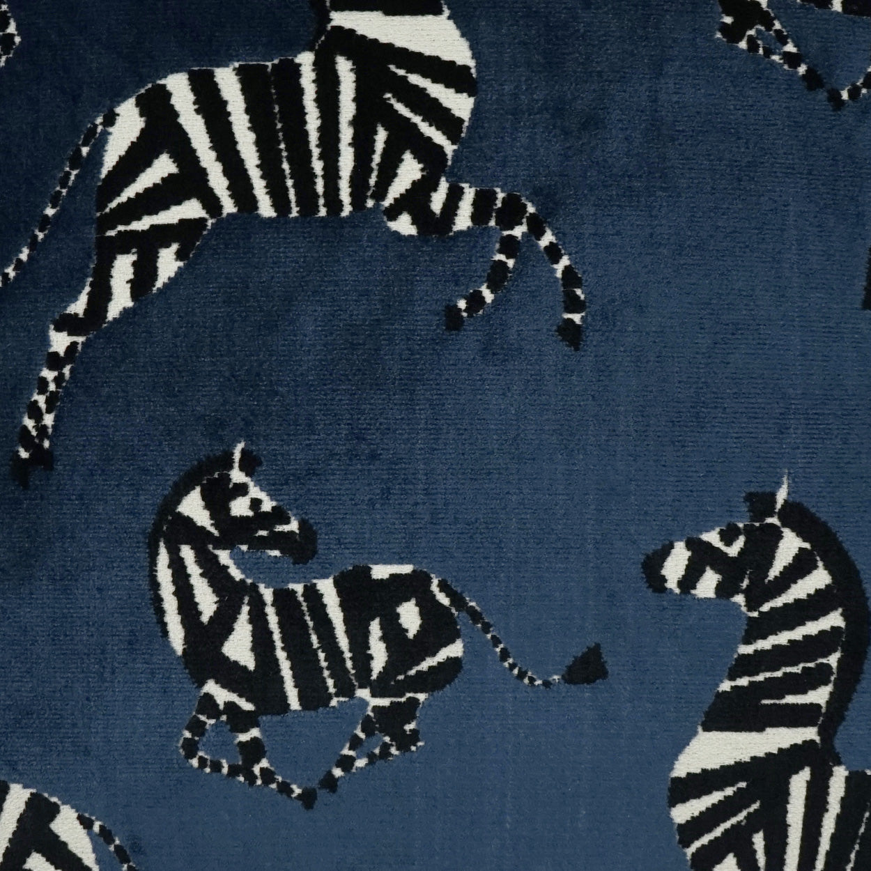 Blue fabric featuring black-and-white zebra silhouettes in various poses, woven texture.