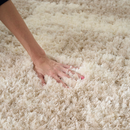 Cream shag rug being pressed by a hand; plush high-pile texture for cozy living room decor.