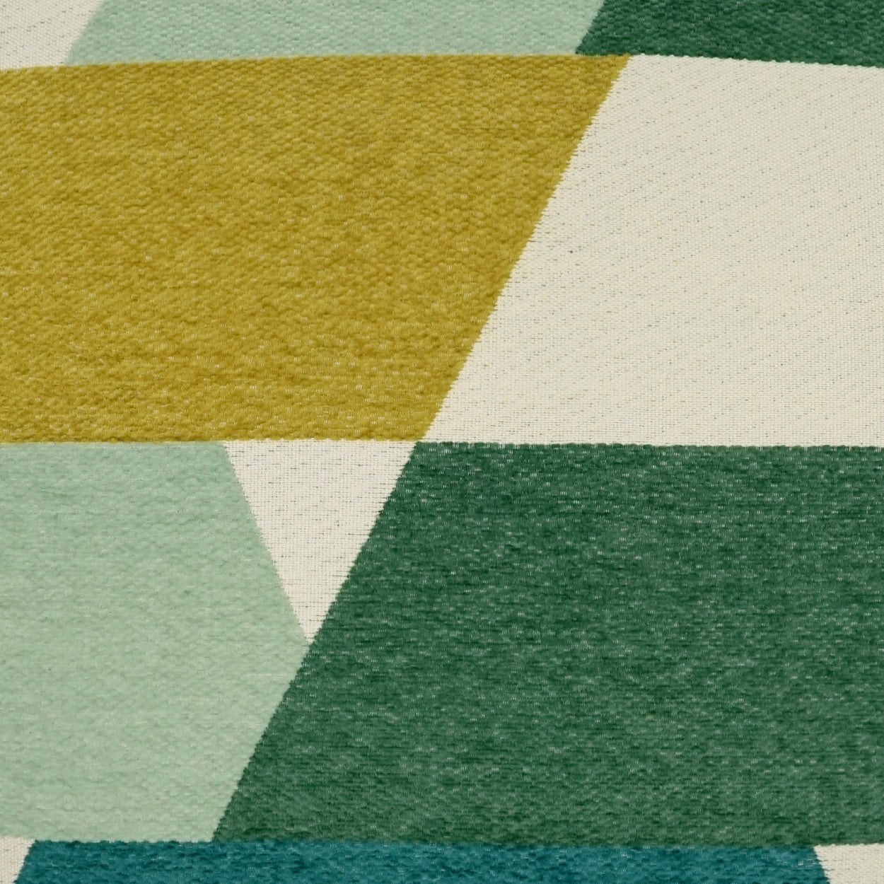 Geometric abstract fabric pattern in green & teal tones with mustard and cream shapes; textured textile.