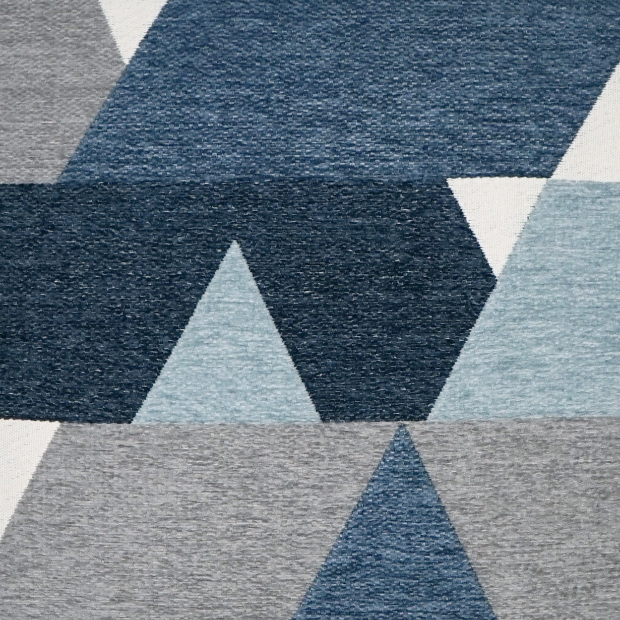 Geometric pillow with navy, sky blue, and light gray triangle patterns.