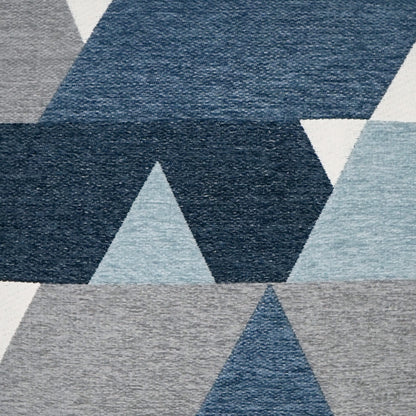 Geometric pillow with navy, sky blue, and light gray triangle patterns.