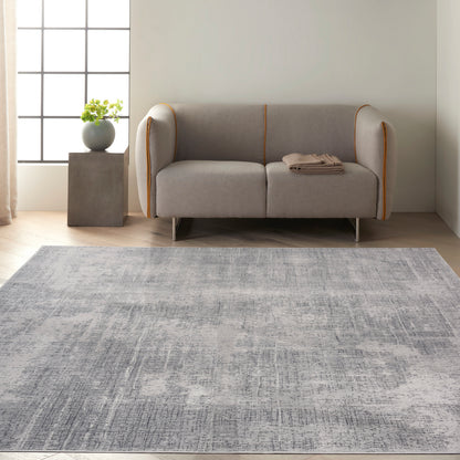 Modern light gray sofa with orange piping, in a minimalist living room with a textured gray rug and potted plant.