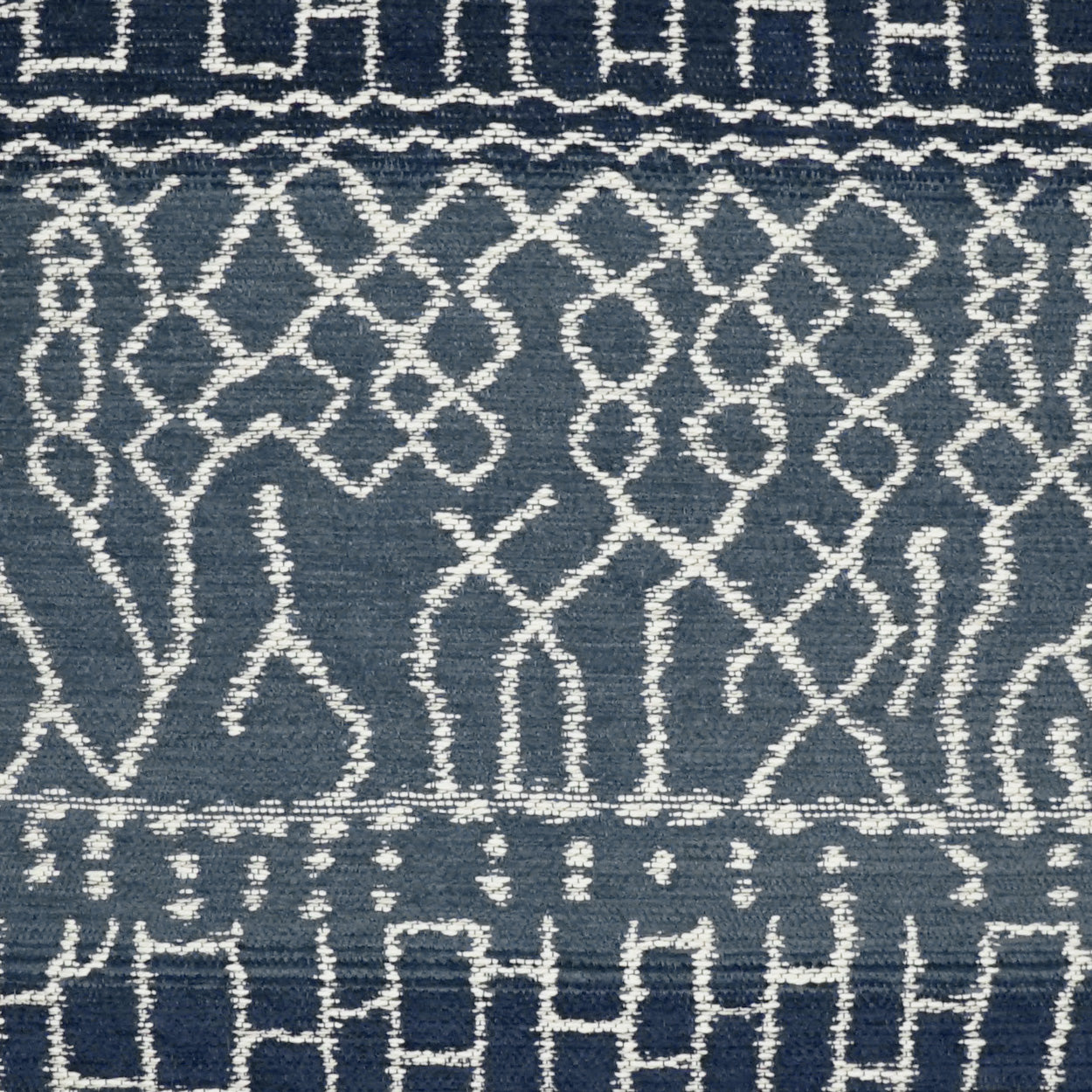 Navy blue fabric with white embroidered geometric lattice pattern and narrow border bands, decorative textile for upholstery.