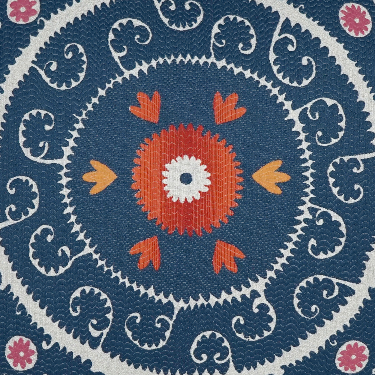 Blue mandala fabric print with concentric rings, orange center flower, white center dot, orange petals, white scrollwork, and pink accents.