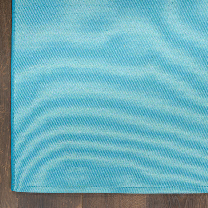 Blue textured rug with a woven grid pattern on a wooden floor.