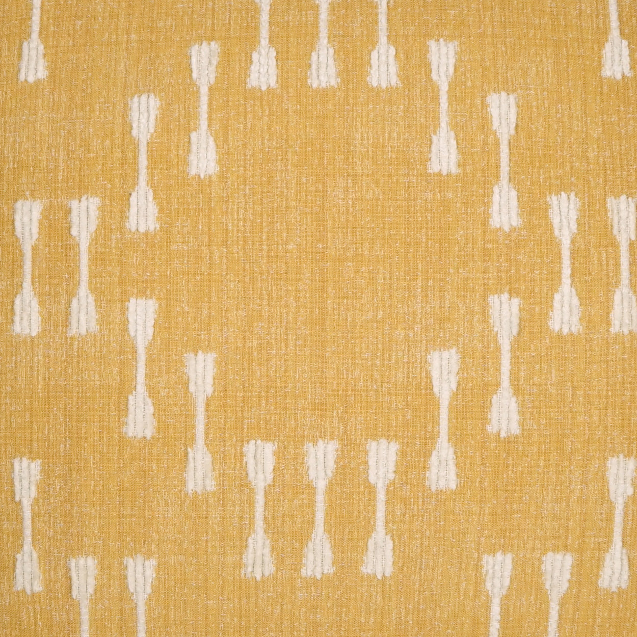 Mustard yellow woven fabric with repeating white tassel motifs and subtle texture.