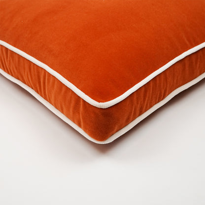 Orange velvet cushion with white piping, corner detail, soft decorative pillow for sofa.