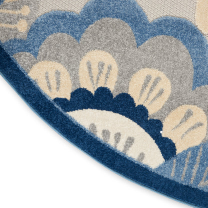 Round rug with blue, cream and beige scallop motif; textured woven surface and curved edge visible.