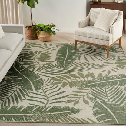 Green tropical leaf-pattern outdoor rug on patio flooring with potted plants, 10' x 14'.