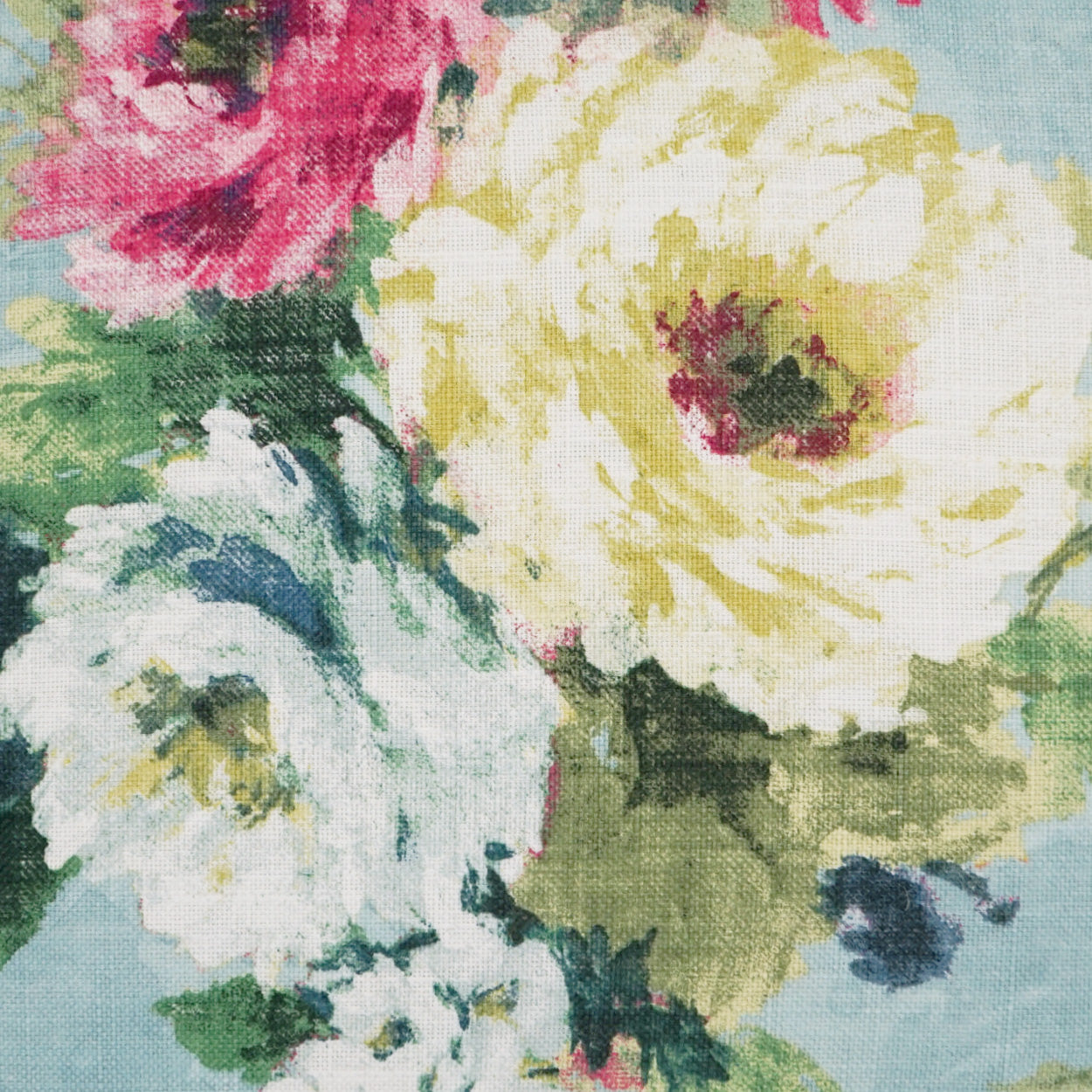 Floral fabric with large yellow and white blooms, pink accents and green leaves on light blue background.