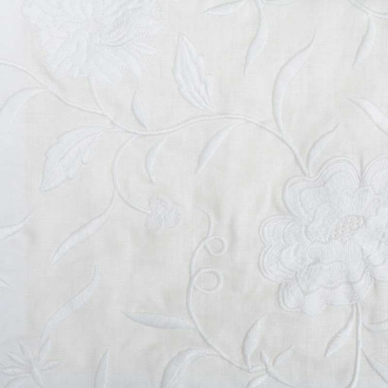 White quilted drapery fabric with raised floral embroidery and flowing vine pattern.