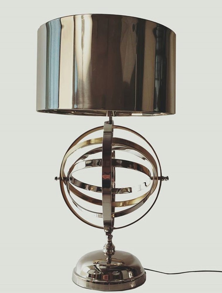 Modern metallic table lamp with circular orbital rings, chrome finish, and a dark chrome drum shade