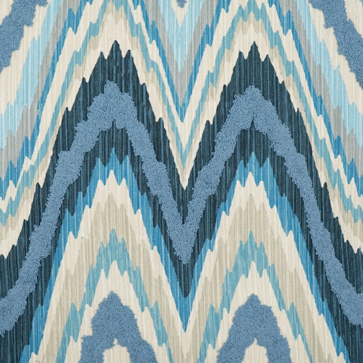 Blue ikat chevron fabric in navy, teal and cream hues; versatile textile for upholstery or pillows.