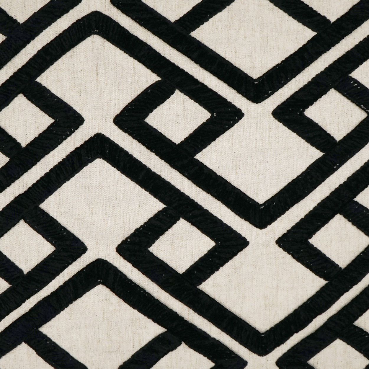 Pillow with beige linen-like fabric and bold black onyx geometric interlocking square/diamond pattern (24 x 24).