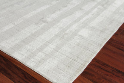 Soft light gray rectangular area rug with subtle striped pattern on dark hardwood floor.
