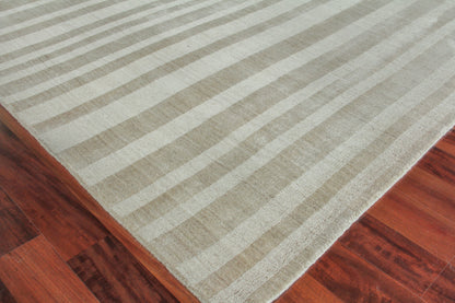 Beige striped area rug on reddish hardwood floor; soft texture with wide light and tan stripes.