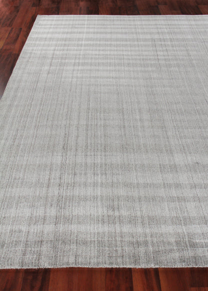 Rectangular light gray hand-loomed rug with subtle striped texture on dark hardwood floor.