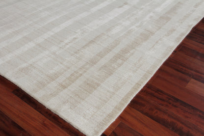 Cream-colored area rug with subtle striped pattern on dark hardwood floor.