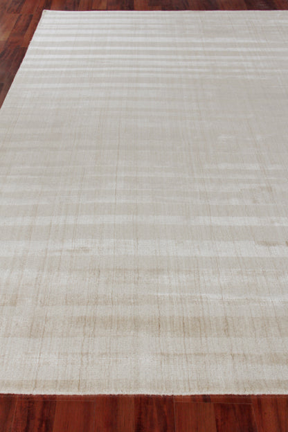 Cream hand-loomed rug with subtle tan stripes on a dark wooden floor.