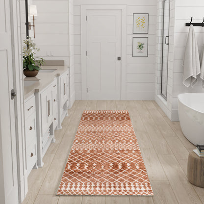 Long orange geometric bathroom runner on light wood floor beside a white vanity and freestanding tub.